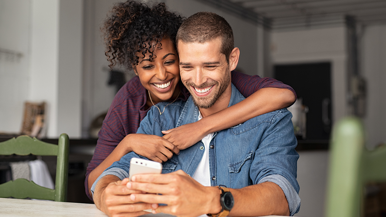 A happy couple looking on a cell phone together